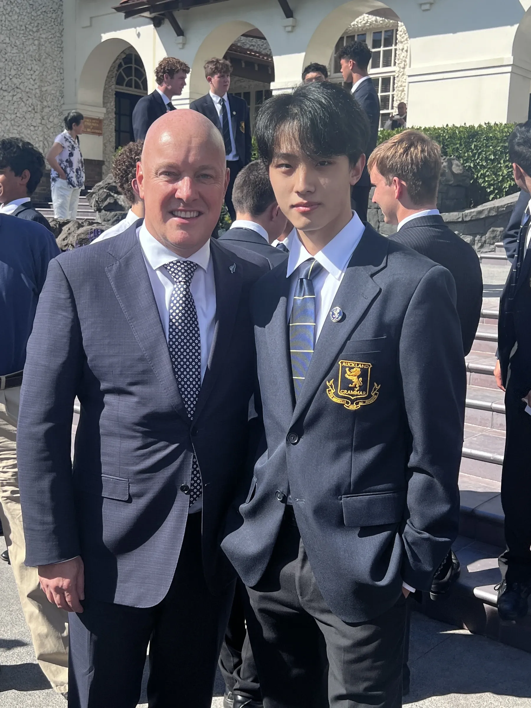 Jeffrey Lin in Auckland Grammar School uniform standing beside New Zealand Prime Minister Christopher Luxon.